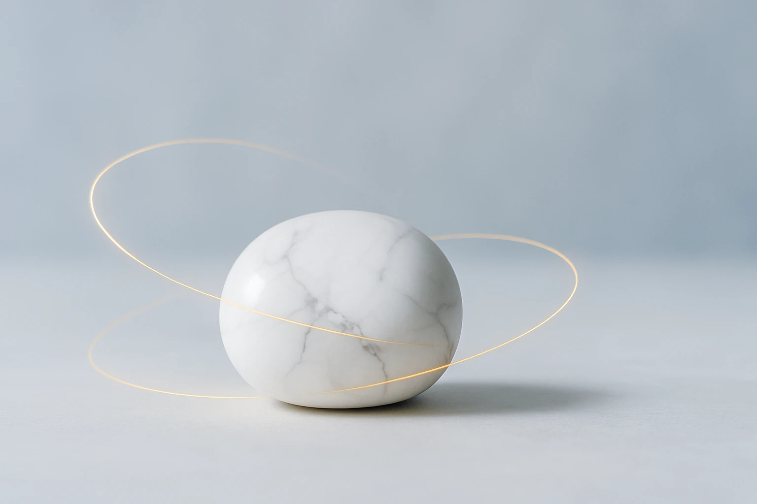 Egy sima, fehér márványgömb, körülötte arany színű vonalak.